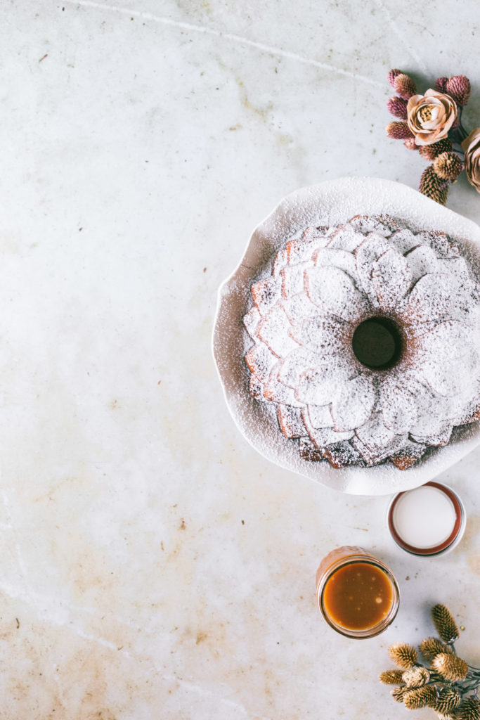 overhead of Salted Caramel Bundt Cake with powdered sugar and salted caramel on the side