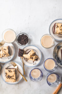 A square slice of A chocolate sheet cake with peanut butter frosting topped with chocolate crunch balls on a small white plate with blue stripes